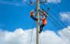 An electrician is on a light pole to maintain a high voltage line on a dangerous electric pole adb 372606618