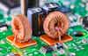 Closeup of toroidal inductors and electrolytic capacitors on electronic PCB